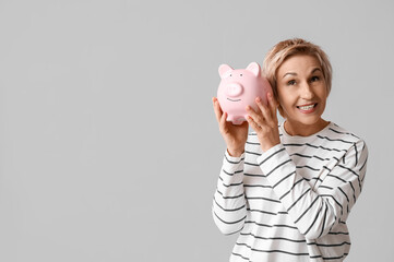 Sticker - Happy mature woman with piggy bank on grey background