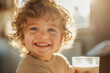 Smiling child in morning sun with glass of milk