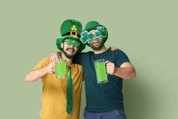 Wall Mural - Happy young men in leprechaun hats with green beards holding glasses of beer on green background. St. Patrick's Day celebration