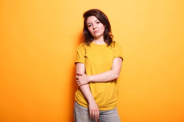 Beautiful young lady stands alone against isolated background, exuding positivity. Joyful caucasian woman strikes a relaxed pose while making eye contact with the camera.