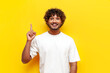 © Богдан Маліцький - I have an idea. young indian man in white t-shirt raises his finger and points up on yellow isolated background, curly guy knows solution and idea