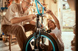 © Marko Geber - Grandfather and grandson working on a bicycle in the garage
