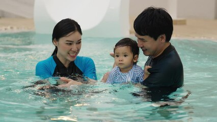 Wall Mural - happy family. father and mother with small daughter playing in swimming pool.