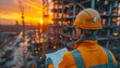 Construction worker in hard hats holding blueprint and checking plans against the backdrop of a stunning sunset over an active building site.