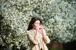 © anatoliy_gleb - Woman allergic suffering from seasonal allergy at spring in blossoming garden at springtime. Young woman sneezing and blowing nose with nasal handkerchief in front of blooming tree. Allergy concept.