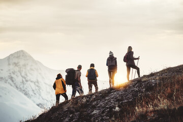 Wall Mural - group of mixed age hikers are standing on mountain slope and looking at sunset