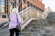 rear view of unrecognizable senior woman walking up stairs, concept of elderly people leisure and active lifestyle, copy space for text