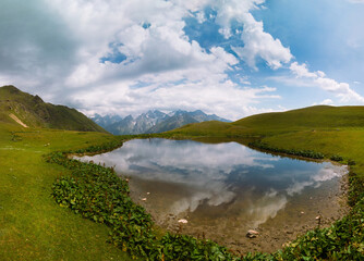 Wall Mural - Aerial view at the Koruldi lakes in Caucasus mountains, Mestia, Svaneti region, Georgia. Summer day, green hills, mountain pasture for livestock, snow mountain peaks. Large panorama high resolution