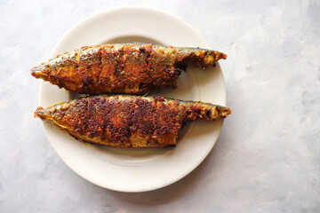 Wall Mural - Indian Mackerel fish fry. Bangda Rava fry. whole Fried fish served on a white vintage plate. also known as talalele bangde in Marathi. Copy space.