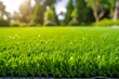 Close-up of artificial grass with a blurred background of trees and sunlight