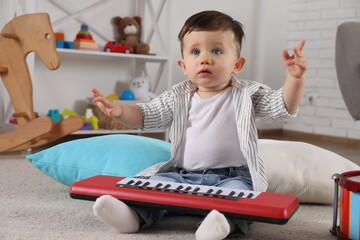 Wall Mural - Cute little boy with toy piano at home