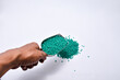 Green masterbatch granules in a hand held shovel, isolated on a white background. This polymer is a colorant for products in the plastics industry