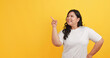 © ronnarong - A chubby Asian woman wearing a white t-shirt is pointing at something on a yellow background.