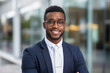 © FutureStock - Portrait of confident African American businessman in eyewear standing with arms crossed in front of company building.