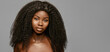 © Beauty Agent Studio - Afro curly Hairstyling and hair care. Beauty fashion portrait of young beautiful african american woman with volume hair against gray background with cope space
