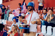 © Drazen - USA sports fan playing drums during match at stadium.