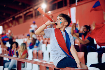 Wall Mural - Kid blowing a vuvuzela during sports match at the stadium.