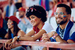 © Drazen - Happy black woman watching sports match with her boyfriend at stadium.