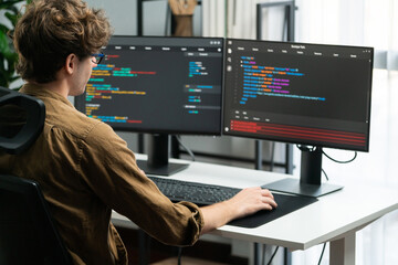 it developer working online software development on pc monitors at modern home office on coding appl