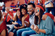 © Drazen - Group of cheerful sports fans celebrating during match at stadium.