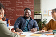 © Mediaphotos - Portrait of smiling African American student enjoying group discussion at table in college classroom. copy space