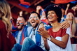 © Drazen - Happy black sports fan and her friends applauding during match at stadium.