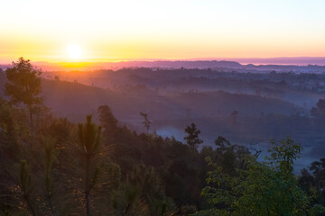 Sunrise over the mountains with rays breaking through the fog 