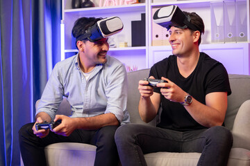 Buddy friend gamers playing video game using joysticks and VR headset of virtual technology in reality in studio room with neon blue light. Comfy living indoor with cheerful fighting winner. Sellable.