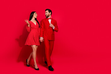 Poster - Full body photo of attractive young couple walk talk dating valentine day dressed stylish elegant clothes isolated on red color background