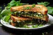 Pesto grilled cheese sandwich overflowing with melted cheese and fresh herbs