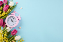 Welcoming Spring: Honoring International Women's Day On March 8th. Top View Photo Of Alarm Clock, Tulips, Mimosa, Hearts On Pastel Blue Background With Advert Space