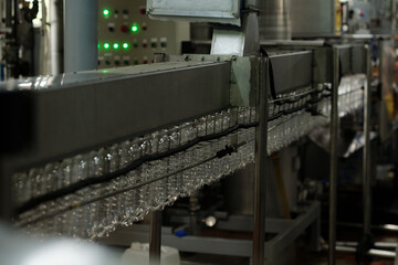 Aufkleber - Part of belt conveyor with clean empty transparent plastic bottles moving along assembly line inside huge industrial machine in factory