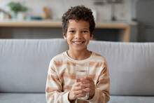 Cheerful Little Black Boy With Bright Smile Holding Clear Glass Of Water