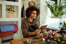 Young Male Florist Working And Using A Tablet In A Flower Shop