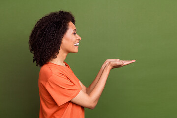 Sticker - Photo of positive cute lady dressed orange t-shirt holding arms empty space smiling isolated khaki color background