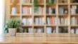 © olz - Potted plant on wooden table with bookshelf background, tranquil study space concept