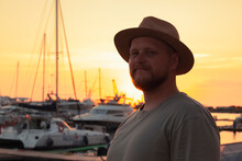 Male Against The Background Of Yachts And Boats Moored At The Seaport And Colorful Sunset. The Seaport Of Sochi.