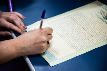 a person is writing with a blue pen on paper in the middle of their hand