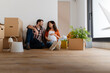 © lordn - Beautiful young couple expecting a baby just moved into an empty apartment, sitting among cardboard boxes making plans for the future. New beginnings