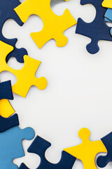 Wall Mural - Blue, yellow, navy pieces of puzzle frame on white background. World autism awareness day concept. Top view, copy space