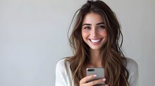 Smiling young woman stares at her mobile phone while texting, messaging and browsing social networks