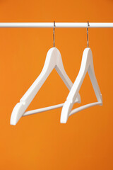 Wall Mural - White clothes hangers on rack against orange background