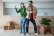 © DimaBerlin - Overjoyed dancing man woman move in new apartment happy about living together. Loving spouses enjoying life changings having fun among cardboard boxes on kitchen during relocation. Buying real estate.
