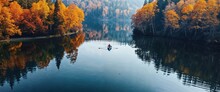 Rowing Boat In A Peaceful Lake Surrounded By Autumn Trees.