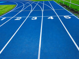 Fototapeta  - Blue running track with starting line numbers one to five. Isolated on blue background for sports and athletics concept. Empty track for copy space and text overlay. Top view of running track.