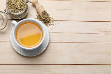 Wall Mural - Fennel tea in cup and seeds on light wooden table, flat lay. Space for text