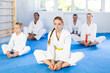 © JackF - Cheerful family, parents and children athletes wearing kimono before training martial arts performs stretching butterfly exercise. Modern positive family chooses active hobby and leisure activity.