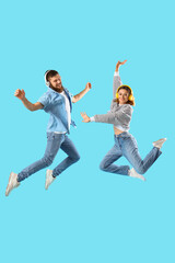 Canvas Print - Happy couple in love with headphones jumping on blue background