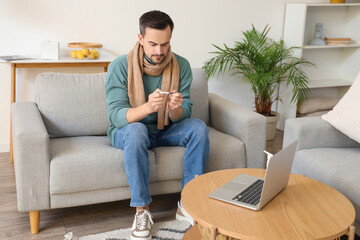 Canvas Print - Ill young man with thermometer video chatting at home