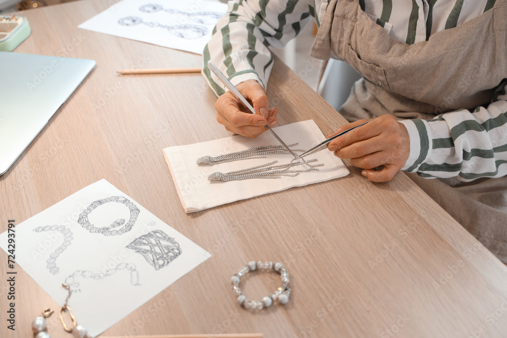 Female jeweler examining earrings at table in workshop, closeup